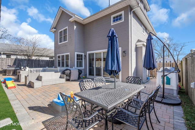 rear view of house with a fenced backyard, a patio, and outdoor dining space