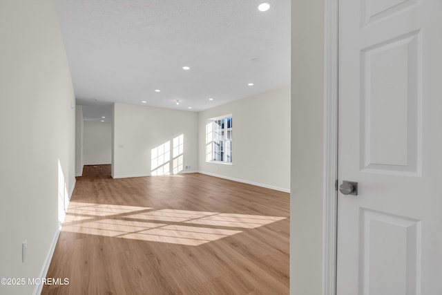 unfurnished room with baseboards, wood finished floors, and recessed lighting