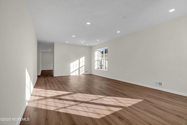 interior space featuring baseboards, visible vents, wood finished floors, and recessed lighting