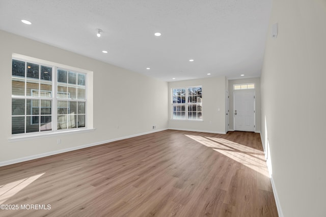 unfurnished living room with baseboards, light wood finished floors, and recessed lighting