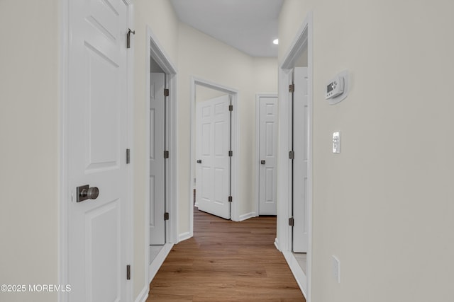 hallway featuring light wood-style flooring and baseboards