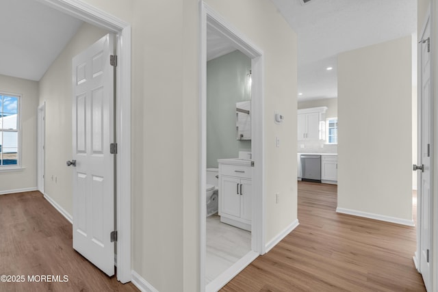 corridor with light wood-style flooring, baseboards, and recessed lighting