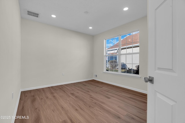 empty room with recessed lighting, wood finished floors, visible vents, and baseboards