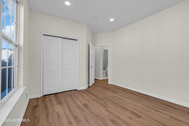 unfurnished bedroom featuring light wood-type flooring, a closet, baseboards, and recessed lighting