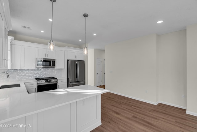 kitchen with decorative backsplash, appliances with stainless steel finishes, wood finished floors, light countertops, and a sink