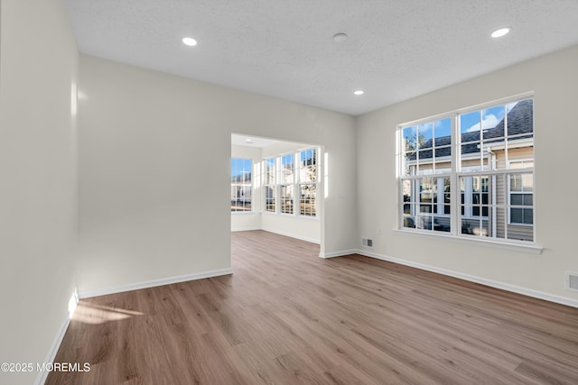 unfurnished room with recessed lighting, a textured ceiling, baseboards, and wood finished floors