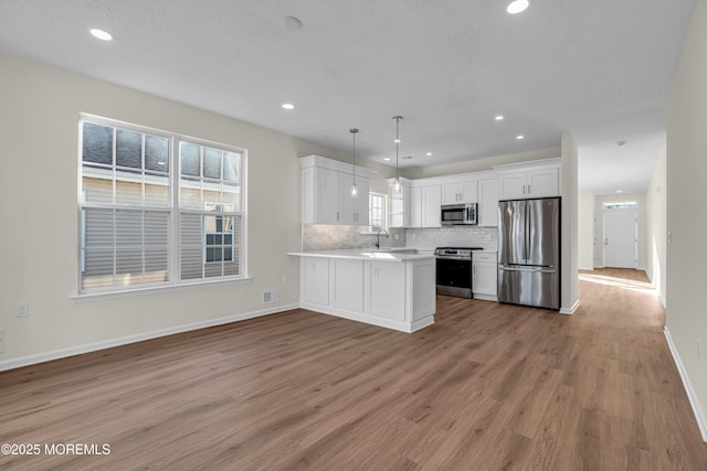 kitchen with stainless steel appliances, light countertops, decorative backsplash, white cabinets, and light wood-type flooring