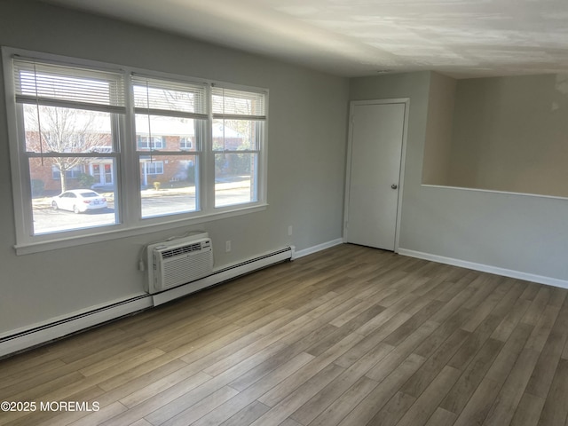 empty room featuring a baseboard radiator, wood finished floors, and baseboards