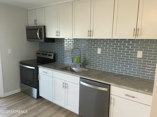 kitchen with stainless steel appliances, light stone counters, backsplash, and a sink