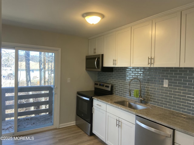 kitchen with white cabinets, decorative backsplash, stainless steel appliances, and a sink