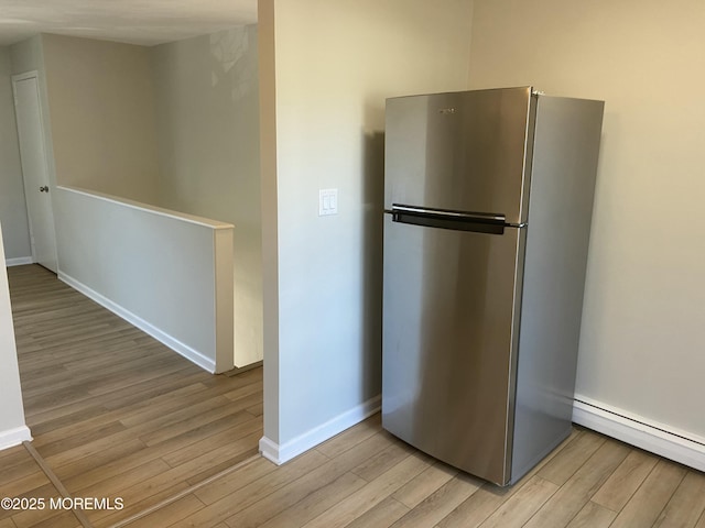 kitchen with light wood-style floors, baseboards, baseboard heating, and freestanding refrigerator