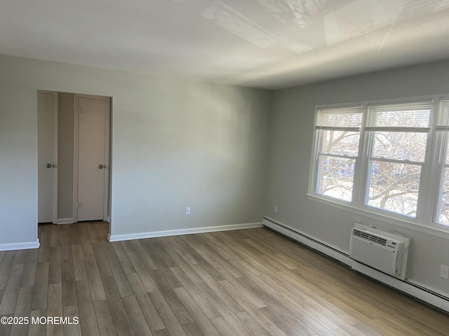 spare room featuring baseboards, baseboard heating, and wood finished floors