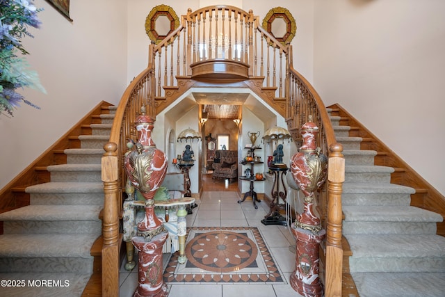 stairway with tile patterned flooring and a high ceiling