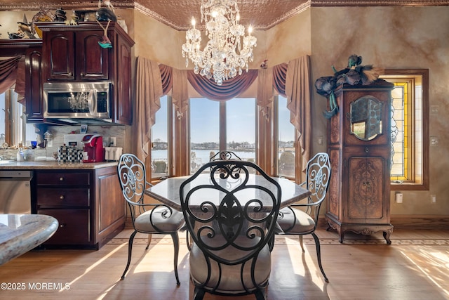 dining space with an inviting chandelier, light wood-style flooring, and baseboards