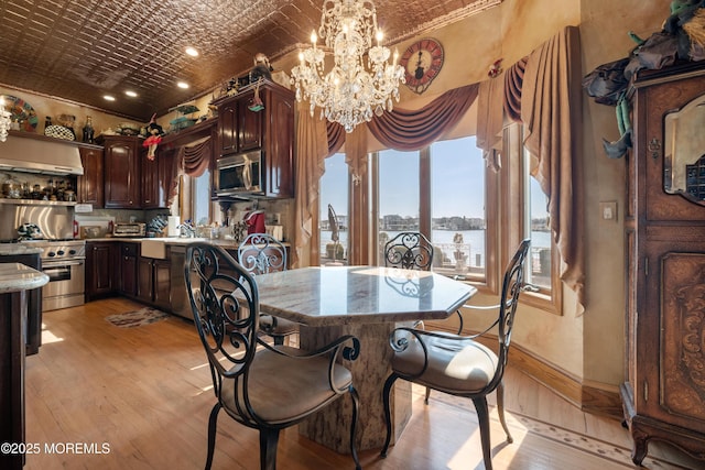 dining space featuring light wood-style flooring, an ornate ceiling, baseboards, and a chandelier