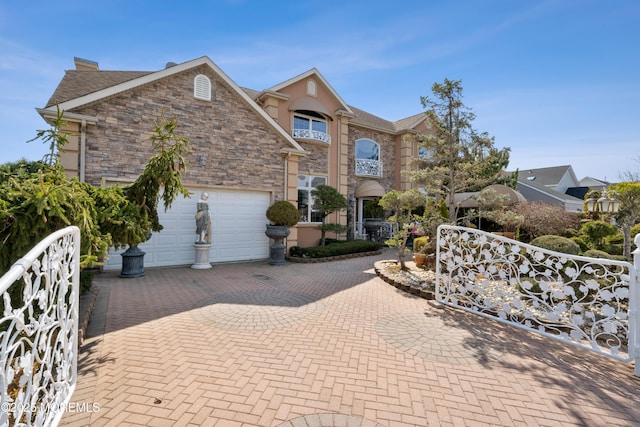 view of front of property with stone siding, an attached garage, a chimney, and decorative driveway