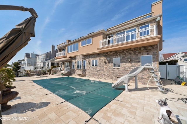 view of swimming pool with fence, a residential view, a water slide, a fenced in pool, and a patio area