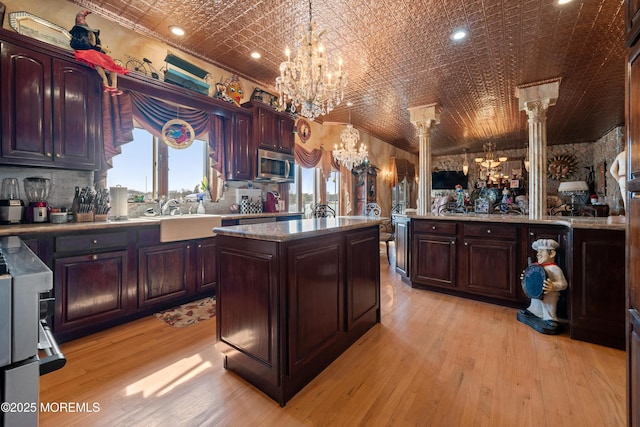 kitchen featuring a chandelier, stainless steel microwave, an ornate ceiling, and a sink