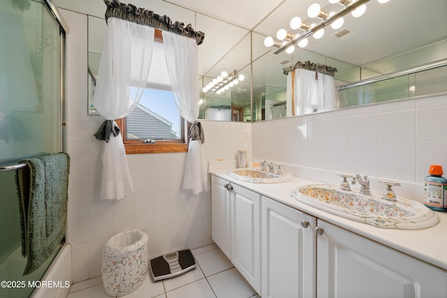 bathroom featuring tile patterned flooring, visible vents, double vanity, tile walls, and a sink