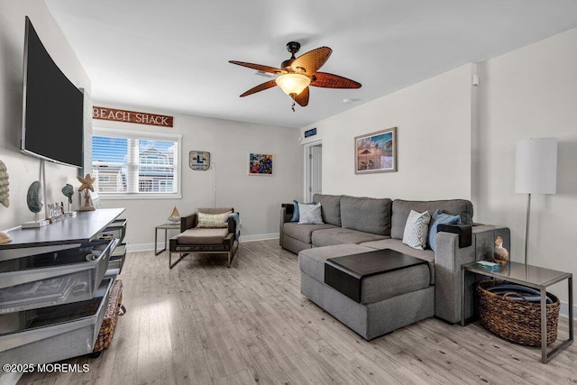 living room with light wood-style floors, ceiling fan, and baseboards