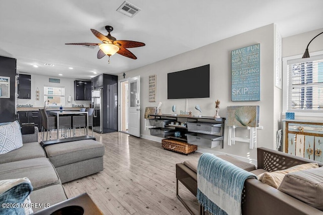 living area with recessed lighting, visible vents, ceiling fan, light wood-type flooring, and baseboards