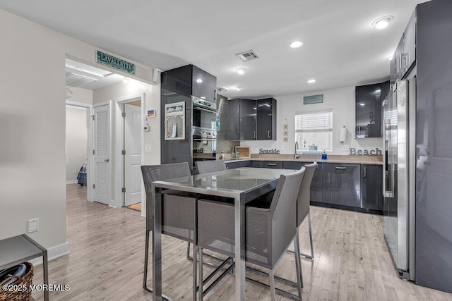 kitchen featuring light wood-style floors, light countertops, dark cabinets, and high end refrigerator