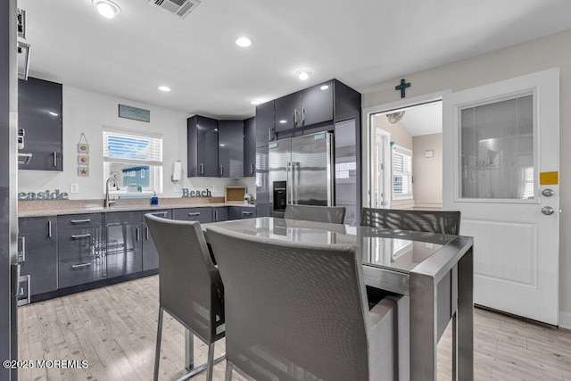 kitchen featuring visible vents, plenty of natural light, light wood-style flooring, and high end refrigerator