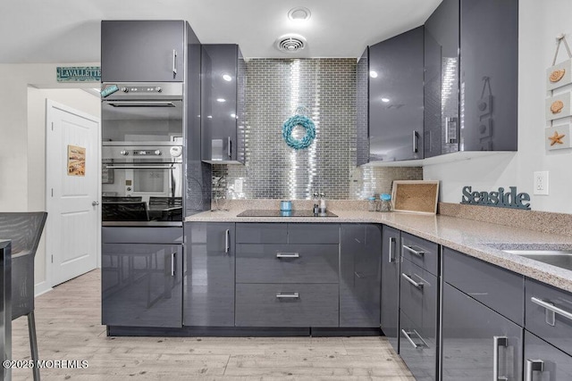 kitchen with visible vents, gray cabinets, black electric stovetop, and double oven