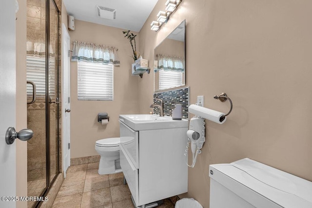 full bath with a stall shower, visible vents, vanity, and toilet