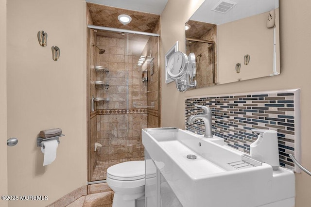 bathroom featuring toilet, a stall shower, backsplash, and visible vents