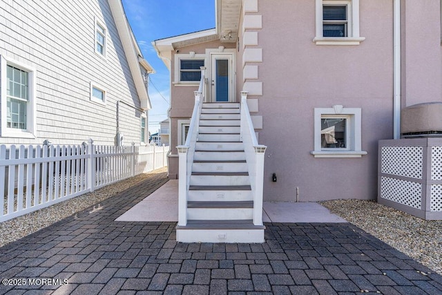 entrance to property with fence, a patio, and stucco siding