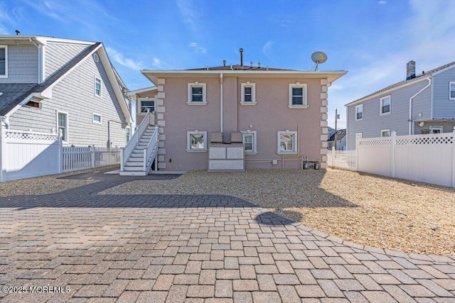 back of house featuring a patio area, a fenced backyard, stairs, and stucco siding