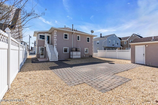 rear view of property featuring a residential view, a fenced backyard, a patio, and stucco siding