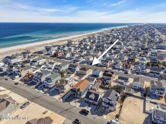 aerial view featuring a view of the beach, a water view, and a residential view