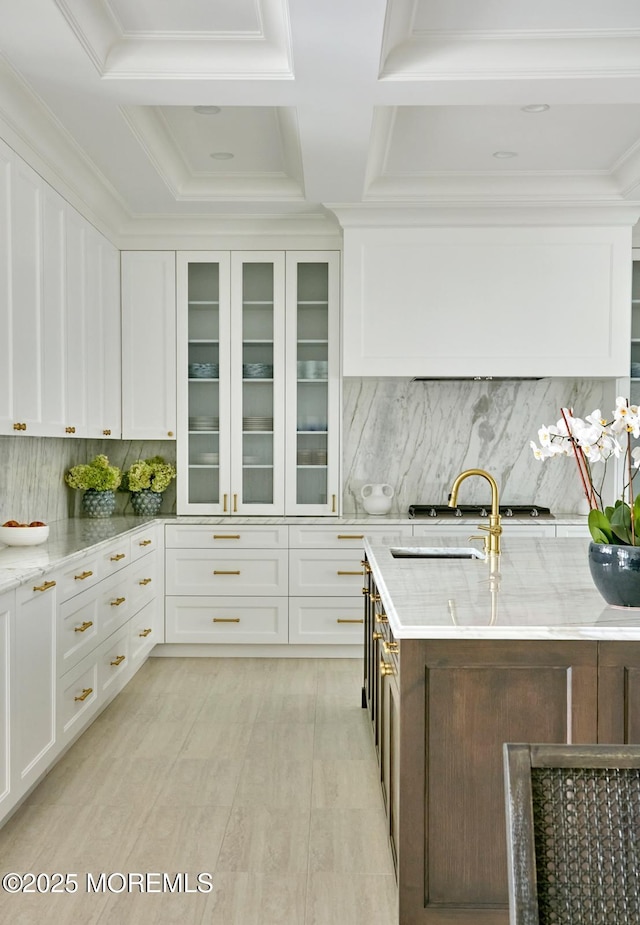 kitchen with light stone counters, a sink, white cabinets, and decorative backsplash