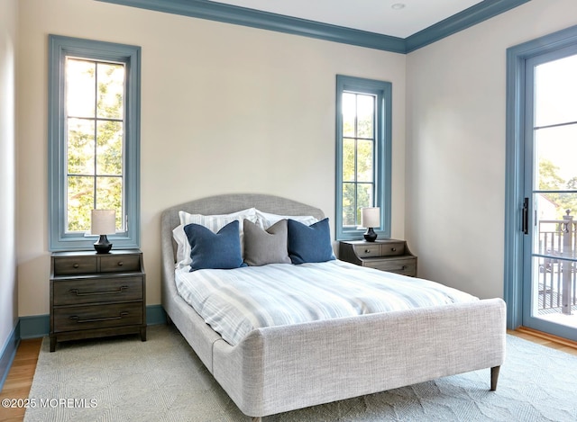 bedroom with baseboards, ornamental molding, light wood-type flooring, and access to exterior