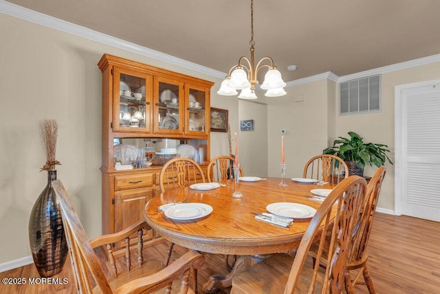 dining room featuring visible vents, a notable chandelier, ornamental molding, light wood-style floors, and baseboards