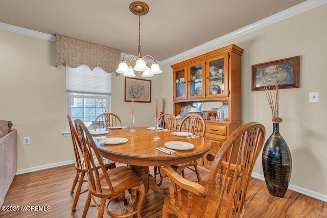 dining room with baseboards, crown molding, and light wood finished floors