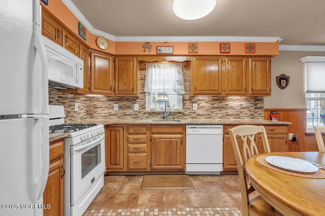 kitchen featuring brown cabinetry, white appliances, crown molding, and a sink