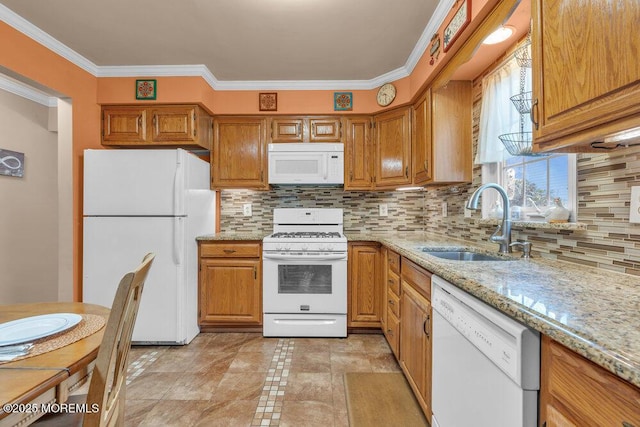 kitchen featuring a sink, white appliances, brown cabinets, and light stone countertops