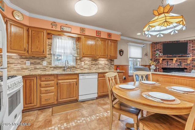 kitchen with pendant lighting, ornamental molding, a fireplace, white appliances, and a sink