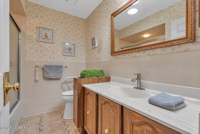 bathroom featuring a wainscoted wall, toilet, wallpapered walls, and vanity