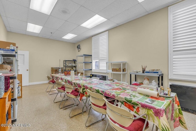 dining space featuring speckled floor, baseboards, and a drop ceiling