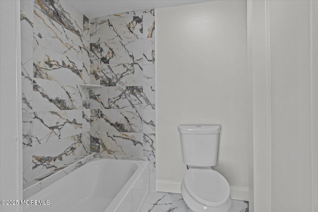 bathroom featuring marble finish floor, bathing tub / shower combination, toilet, and baseboards