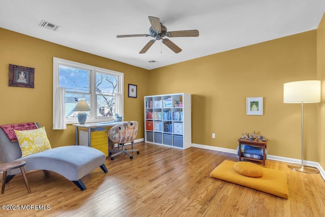 living area with visible vents, baseboards, and wood finished floors