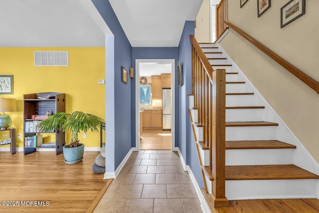 stairs with visible vents, baseboards, and wood finished floors