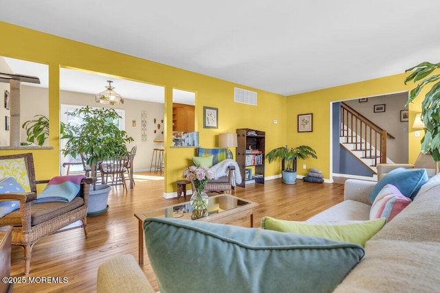 living room with baseboards, stairs, visible vents, and wood finished floors