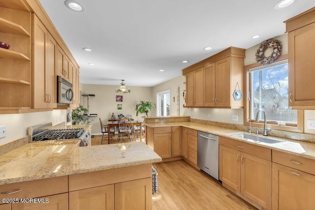 kitchen featuring light wood-style flooring, appliances with stainless steel finishes, a peninsula, open shelves, and a sink