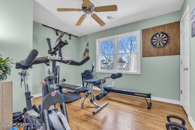 exercise room featuring baseboards, visible vents, ceiling fan, and wood finished floors