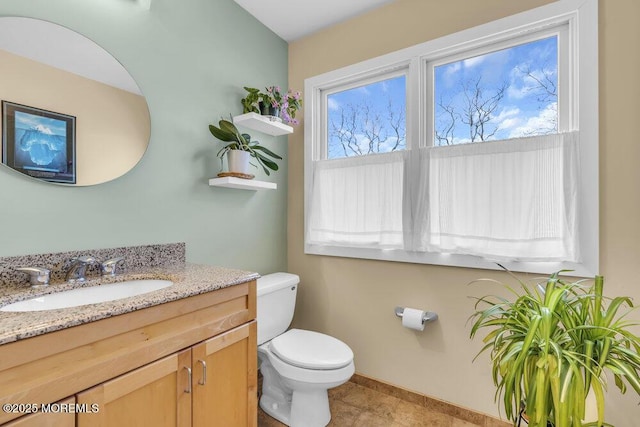 bathroom with toilet, baseboards, and vanity